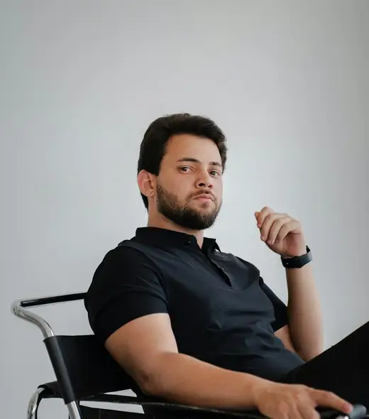 Man in a black polo shirt seated in a chair